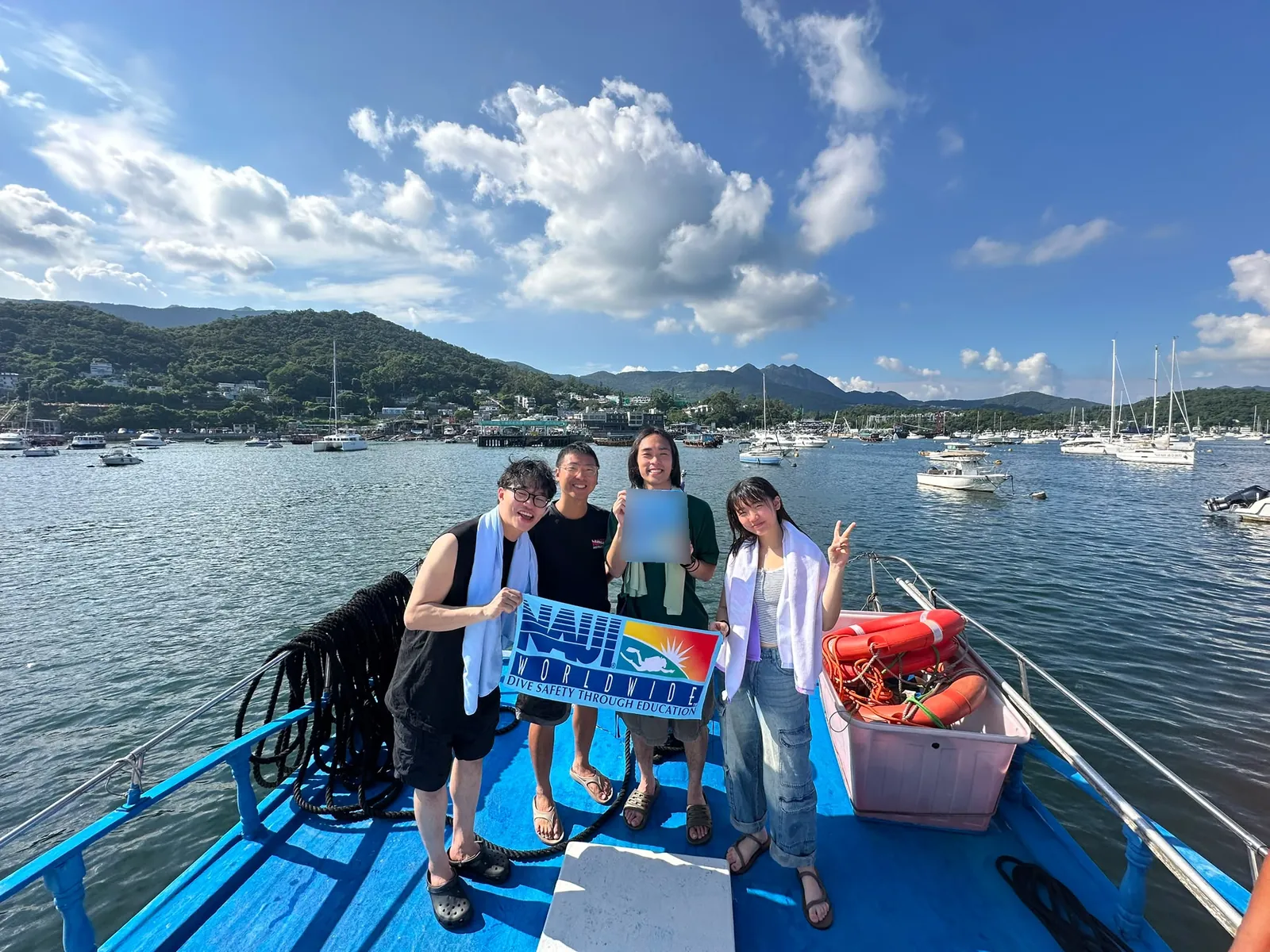 香港 NAUI 潛水課程|香港潛水學校提供的課程紀錄:船上四名參與者手持NAUI旗幟的真實課程合照,證書個人資料已遮蔽